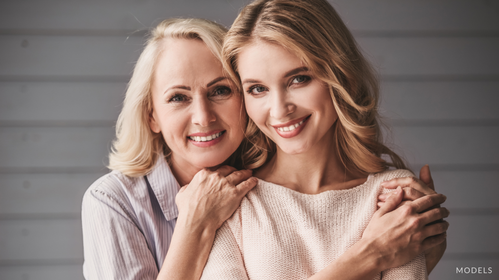 An older and younger woman hugging and smiling (models)